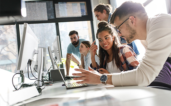 group of young professionals collaborating at computers in a modern workspace discussing project ideas and strategies for success in teams of eight